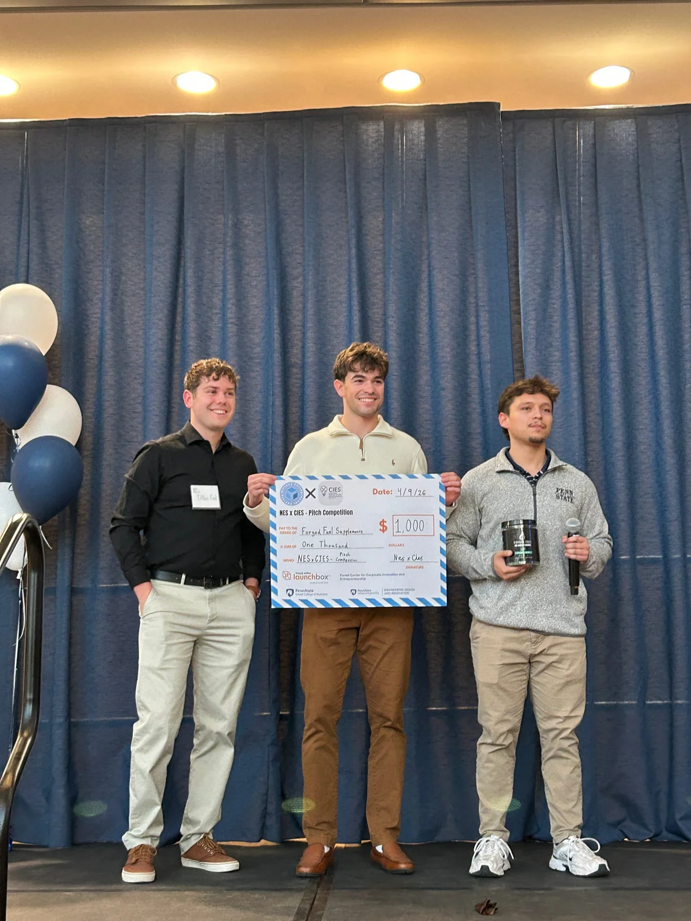 NES × CIES pitch competition participants holding a $1,000 prize check